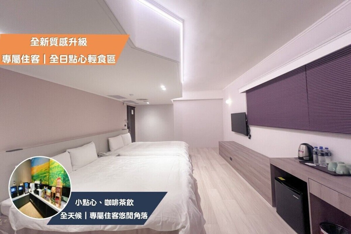 A modern hotel room with a large bed, a small desk, and a TV mounted on the wall.