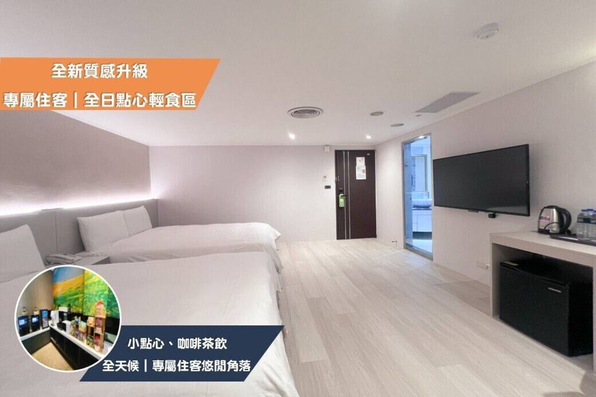Ein modernes Hotelzimmer mit einem großen Bett, einem Flachbildfernseher und einer kleinen Küchenzeile.