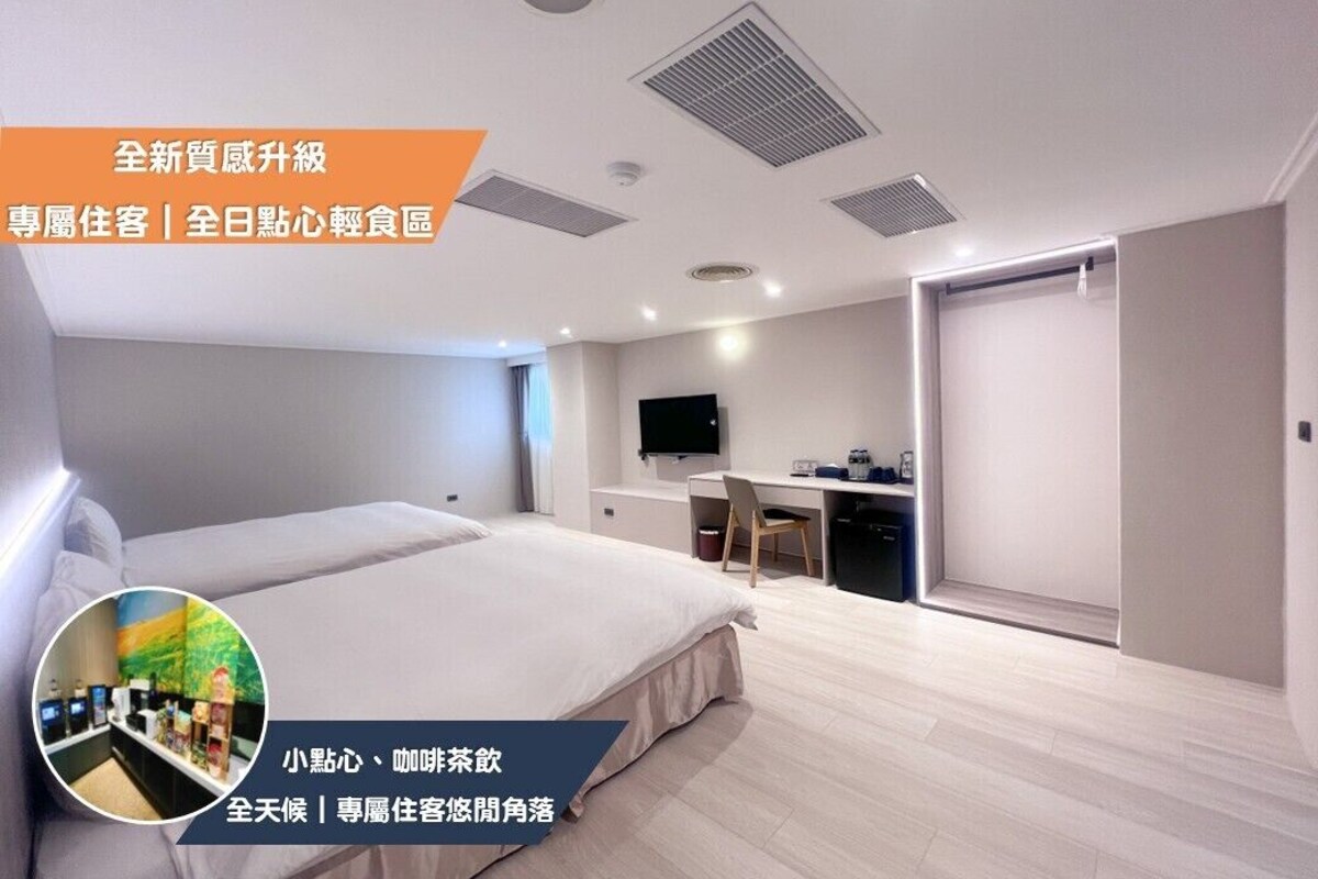 A modern hotel room with two beds, a desk, and a television.