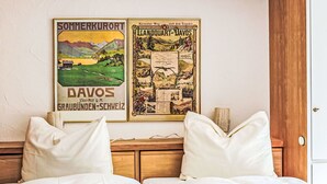 Habitación de hotel con dos camas, ropa de cama blanca y dos carteles en la pared.
