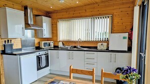 Une cuisine compacte dotée d’appareils électroménagers modernes, de meubles de rangement en bois et d’un coin repas avec une table et des chaises.