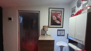 A compact kitchen with a wooden countertop, a refrigerator, and a microwave. There is a framed poster on the wall and a small stool near the counter. - FreeStayle Home (Callao)