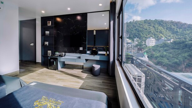 A modern hotel room with a large window, a bed, a desk, and a small seating area. - Cat Ba Nam Phong Hotel (Hai Phong)