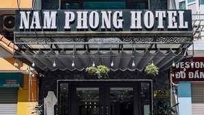 The exterior of Nam Phong Hotel with a prominent sign, a covered entrance, and a small outdoor seating area. - Cat Ba Nam Phong Hotel (Hai Phong)