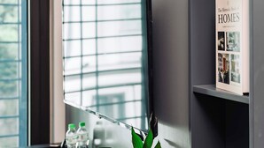 A modern room with a flat-screen TV mounted on the wall, a small potted plant on the desk, a kettle, and a remote control. - Cat Ba Nam Phong Hotel (Hai Phong)