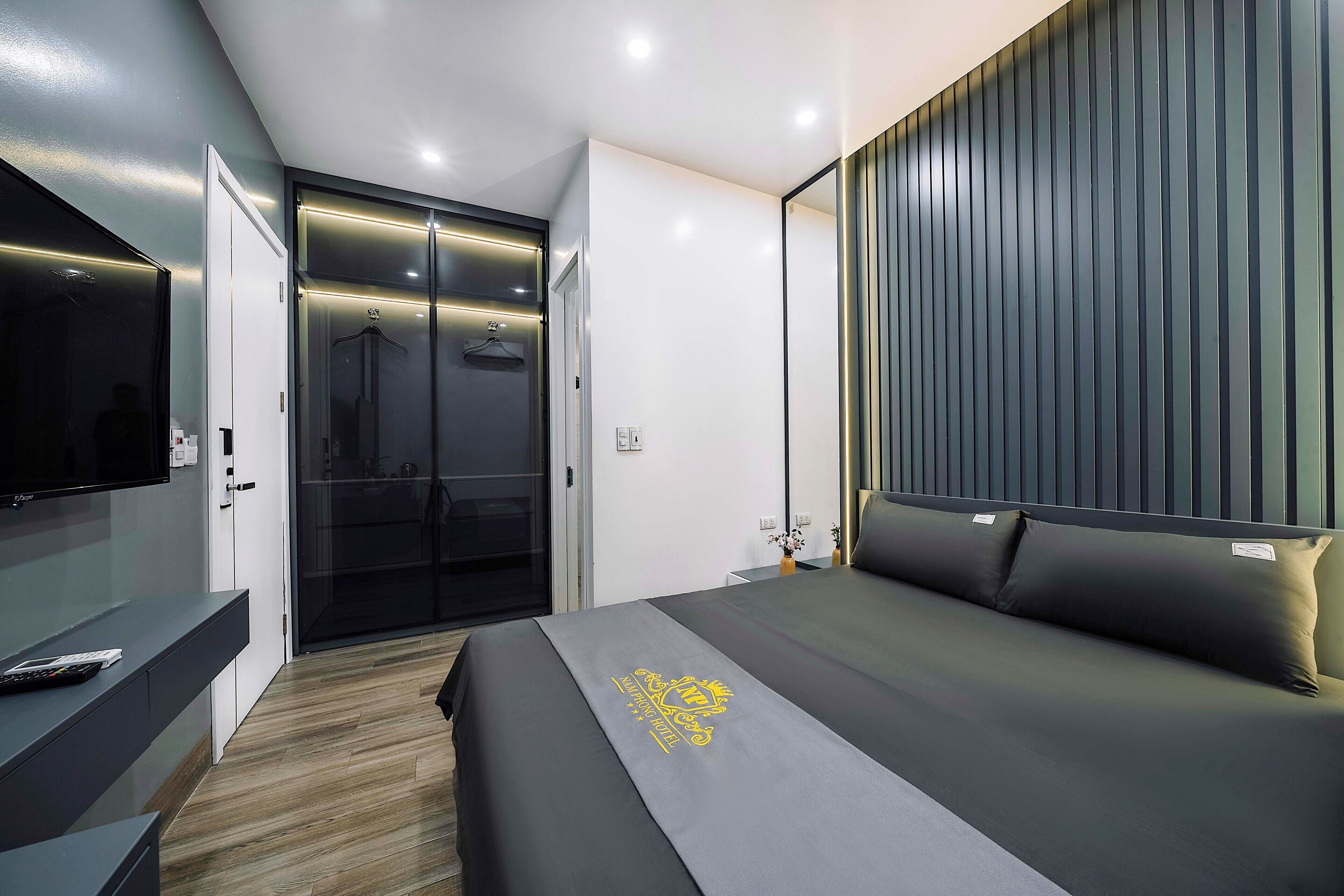 A modern hotel room with a bed, a TV, a wardrobe, and a sliding door.
