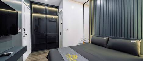 A modern hotel room with a bed, a TV, a wardrobe, and a sliding door.