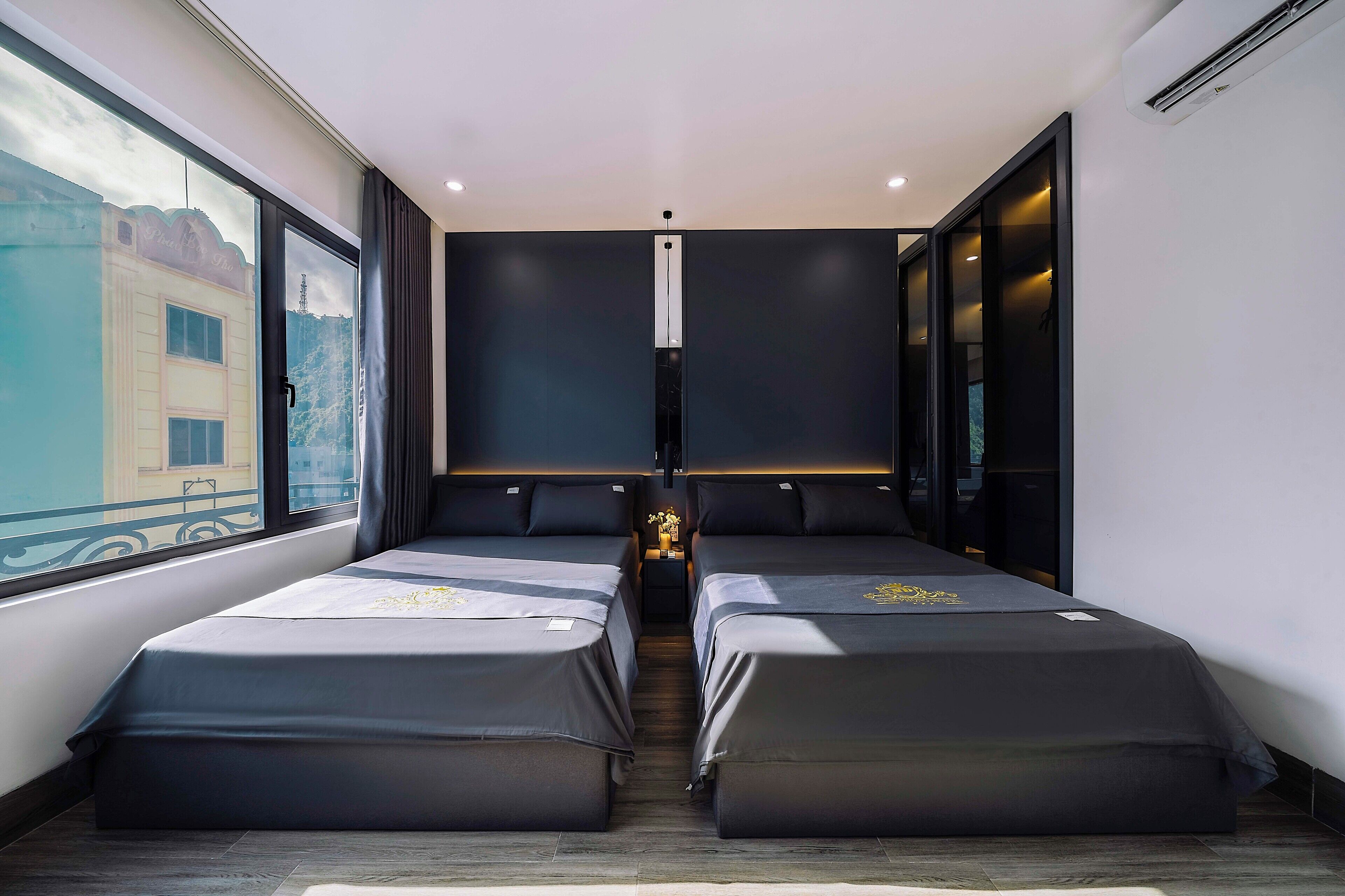 Een moderne hotelkamer met twee bedden, een groot raam en uitzicht op een gebouw.