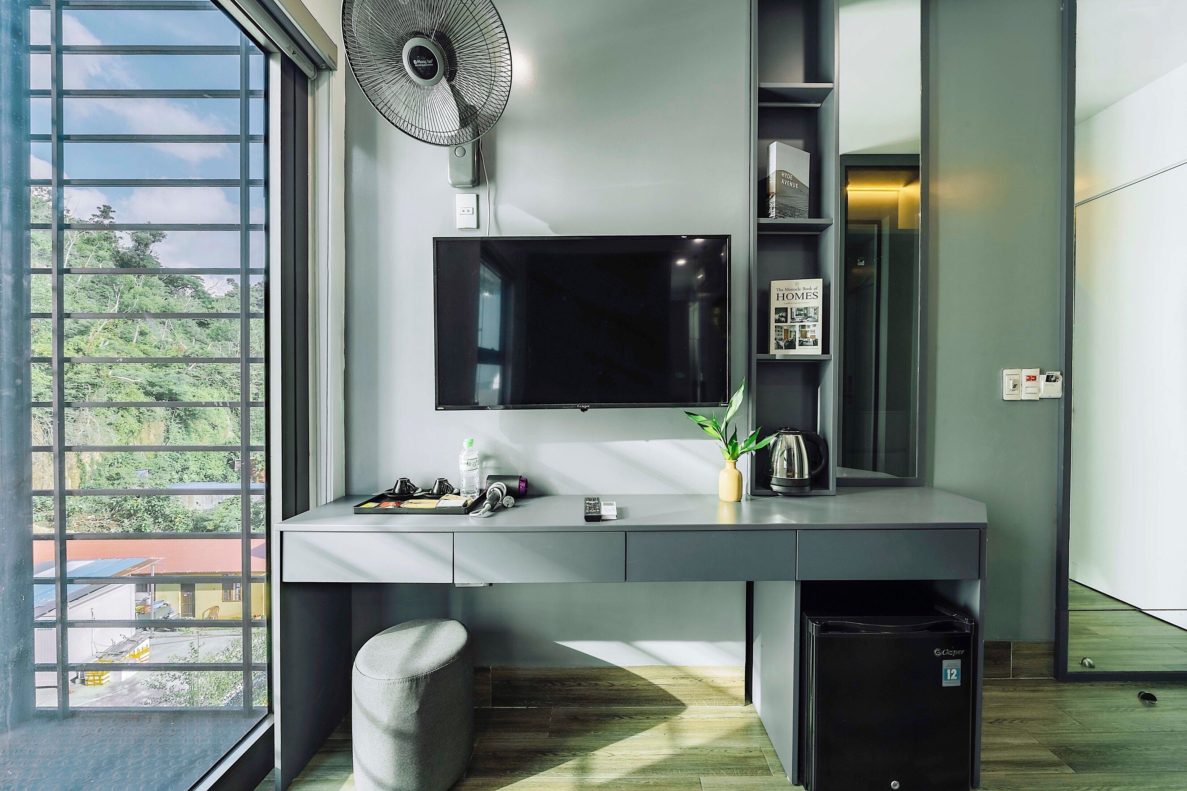 Un espace de bureau moderne comprenant un bureau, une chaise, un téléviseur et un petit réfrigérateur.