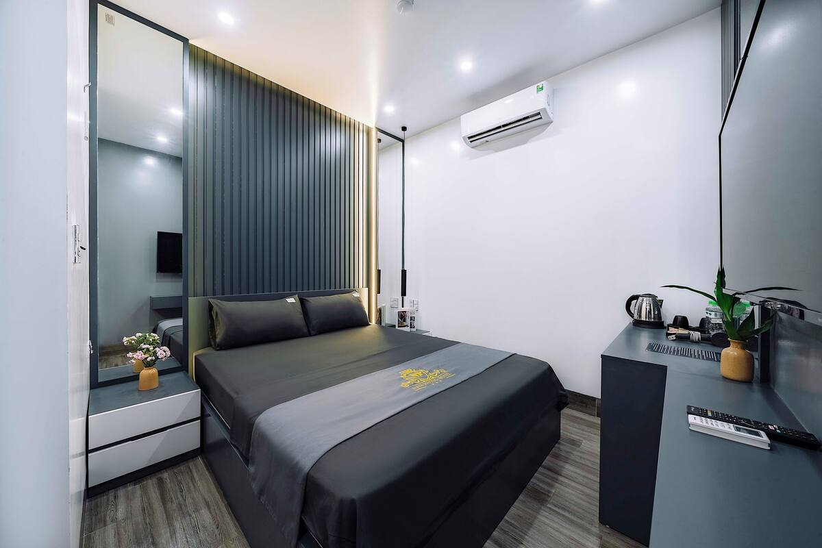 Une chambre d’hôtel moderne avec un grand lit, des tables de chevet, un bureau et un miroir.