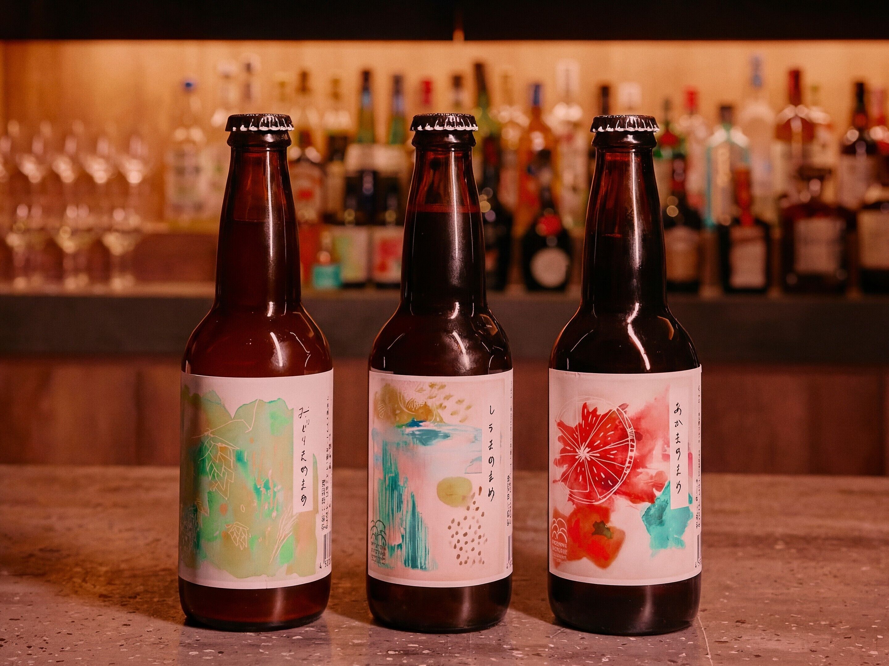 Three bottles with colorful labels on a bar counter.