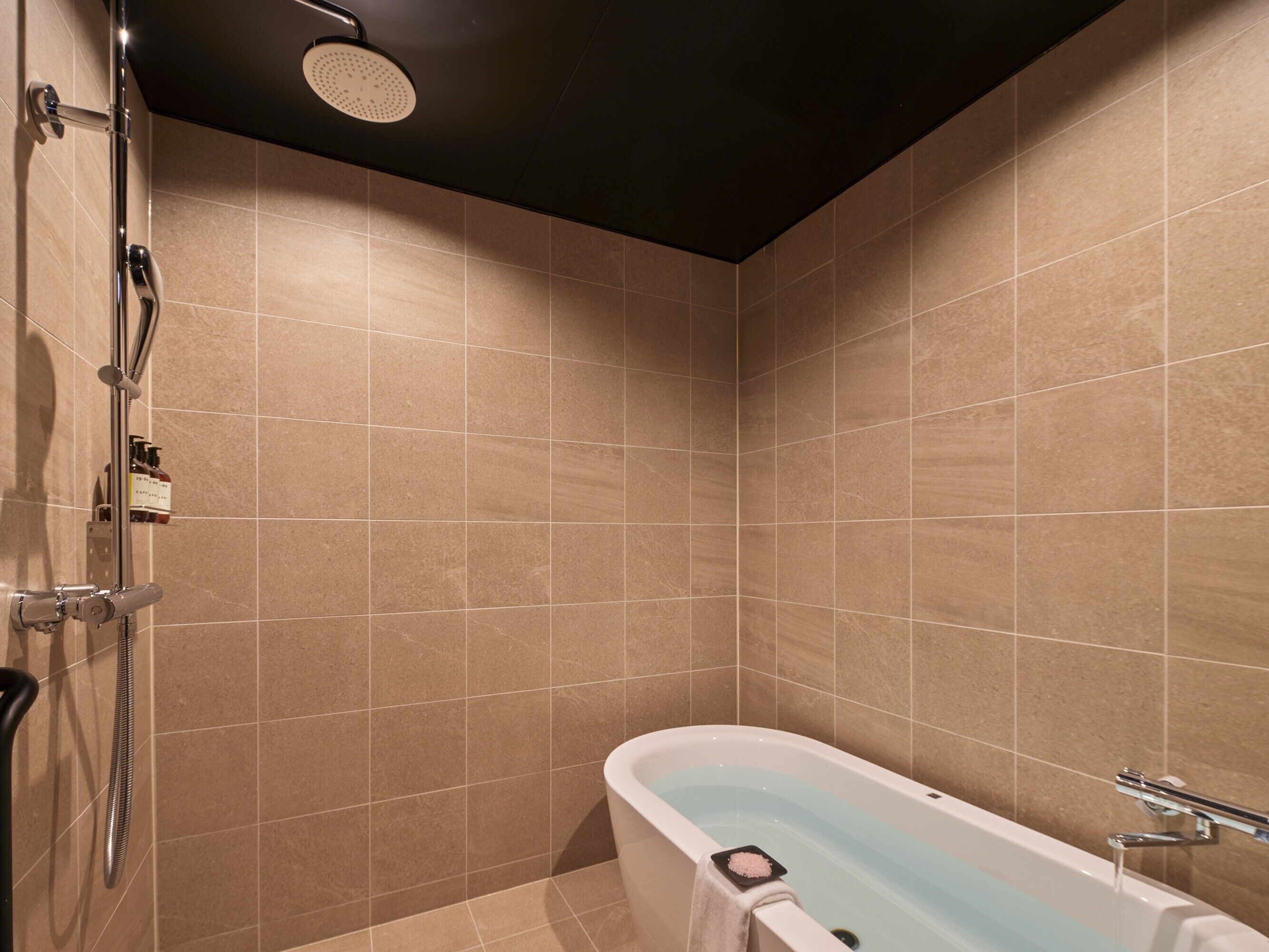 Un baño moderno con bañera, ducha y paredes de azulejos.