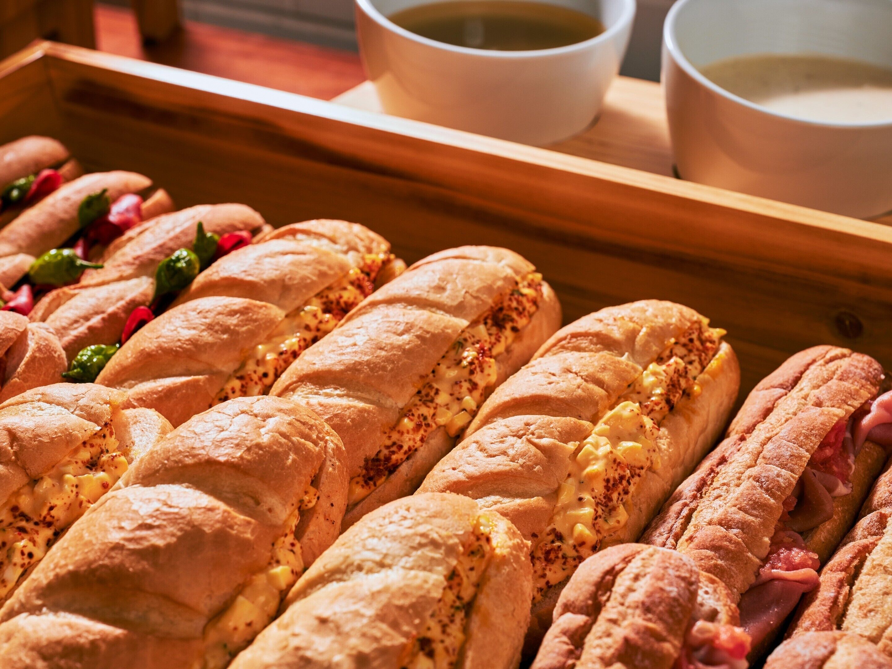 Uma bandeja com vários sanduíches de diferentes recheios, acompanhada por duas xícaras de chá.