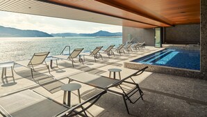 Un espace piscine avec des chaises longues et vue sur la mer.