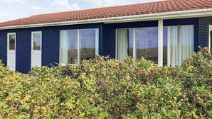 A single-story house with a dark blue exterior, white-framed windows, and a red-tiled roof. - 6 Person Holiday Home in Lundby (Lundby)