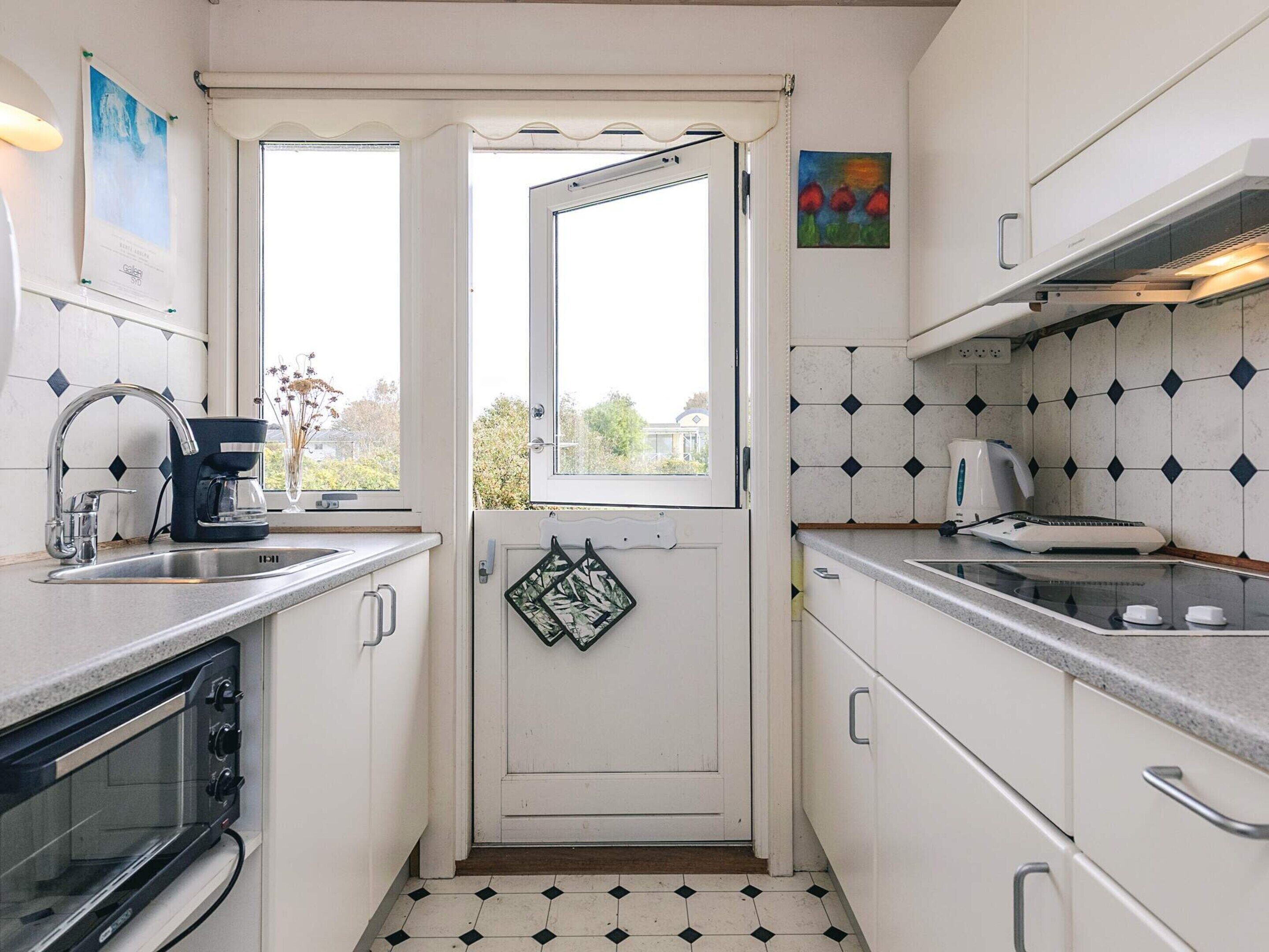 Uma cozinha compacta com forno embutido, cafeteira e micro-ondas.