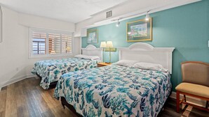 Une chambre avec deux lits, une fenêtre avec des volets, une chaise et un tableau accroché au mur.