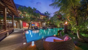 Uma área de piscina com deck de madeira, espreguiçadeiras e uma piscina pequena.