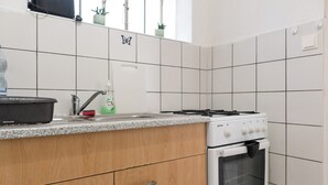 A kitchen with white tiled walls, a stove, oven, and wooden cabinets. - Elegant Room Shared Apt Heart of Vienna (Vienna)