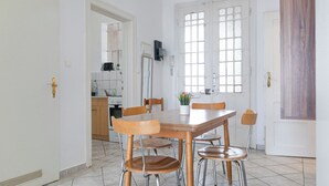 A dining area with a wooden table and chairs, a white door, and a kitchen in the background. - Elegant Room Shared Apt Heart of Vienna (Vienna)