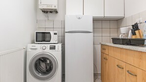 A compact kitchen with a washing machine, microwave, and refrigerator. - Elegant Room Shared Apt Heart of Vienna (Vienna)