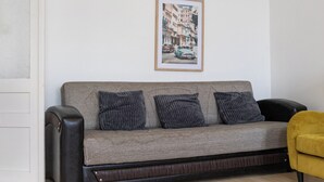 A grey sofa with three dark cushions, a framed picture on the wall, and a yellow armchair. - Elegant Room Shared Apt Heart of Vienna (Vienna)