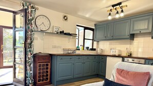 Uma cozinha moderna com armários azuis, uma mesa de jantar de madeira e uma almofada estampada em uma cadeira.