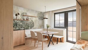 A modern dining area with a wooden table and chairs, a bench, and a large window with a mountain view. - Apartment fur bis zu 4 Personen (Kaprun)