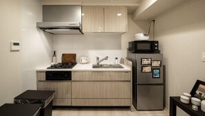 A compact kitchen with a built-in stove, sink, and a refrigerator with magnets. - Mondomio Sapporo 207 (Sapporo)