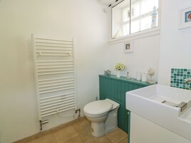 Un baño con un radiador blanco, un inodoro, un tocador verde y un lavabo blanco.