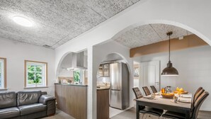 Cozinha moderna com ilha central, eletrodomésticos de aço inoxidável e área de jantar com mesa e cadeiras.