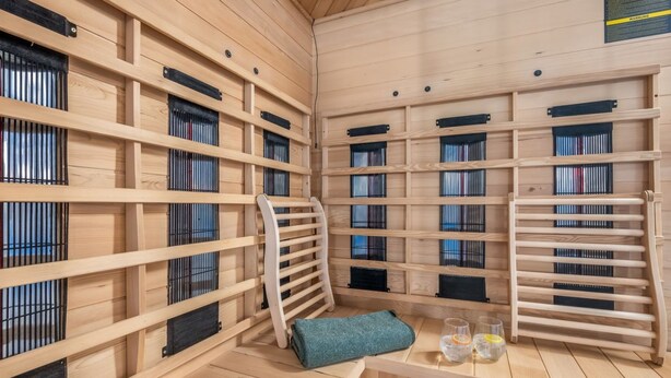 Uma sala de sauna com bancos de madeira, toalha e copos de água.