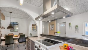 Uma cozinha moderna com uma ilha central, forno embutido e exaustor de aço inoxidável.