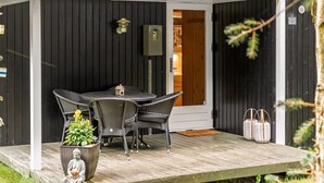 Ein überdachter Außenbereich mit Tisch und Stühlen, einer kleinen Buddha-Statue und einem Blumentopf.