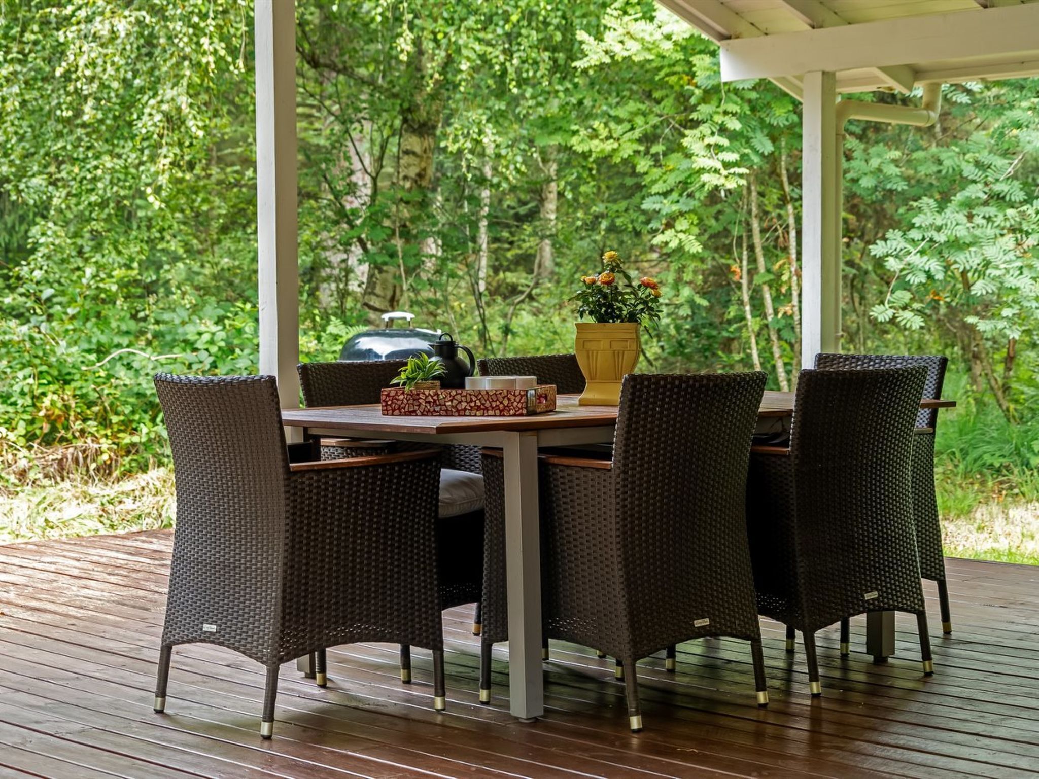 Un área de comedor al aire libre con una mesa y sillas, rodeada de abundante vegetación.