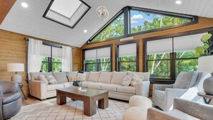 Un salón amplio con un sofá modular grande, una mesa de centro y vistas al exterior a través de ventanales.