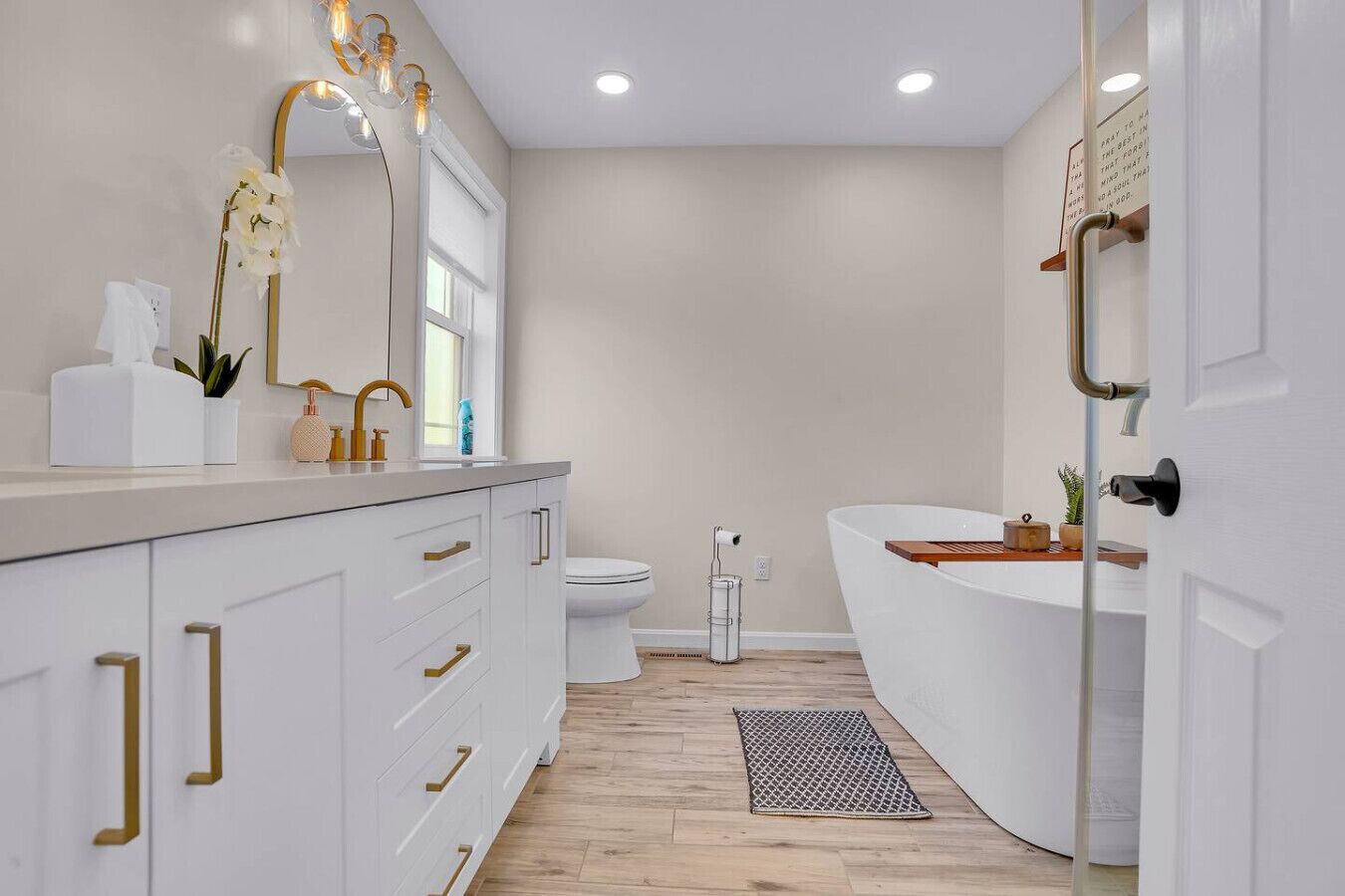 A modern bathroom with a white vanity, a freestanding bathtub, and a toilet.