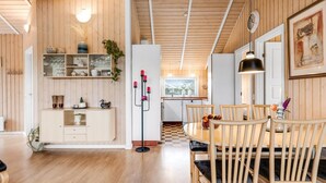 A spacious kitchen with wooden cabinets, a dining area with a round table and chairs, and a view of the outdoors through a window.
