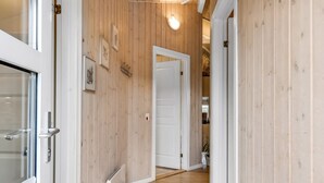 A wooden-paneled hallway with white doors, a radiator, and framed pictures on the wall.
