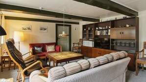 Ein Wohnzimmer mit einer Couch, Sesseln, einem Couchtisch, einem Bücherregal und einem Fernseher.