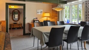Ein Essbereich mit Tisch, Stühlen, einer Lampe und Blick durch große Fenster.