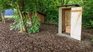 Eine hölzerne Abort auf einer Waldlichtung mit Mulch als Bodengrund.