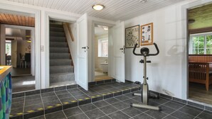 Ein modernes Interieur mit einer Treppe zu einem anderen Raum, einem Wand-Trainingsgerät und einem gefliesten Boden.