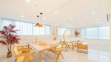 A modern, well-lit dining area with wooden furniture and large windows.