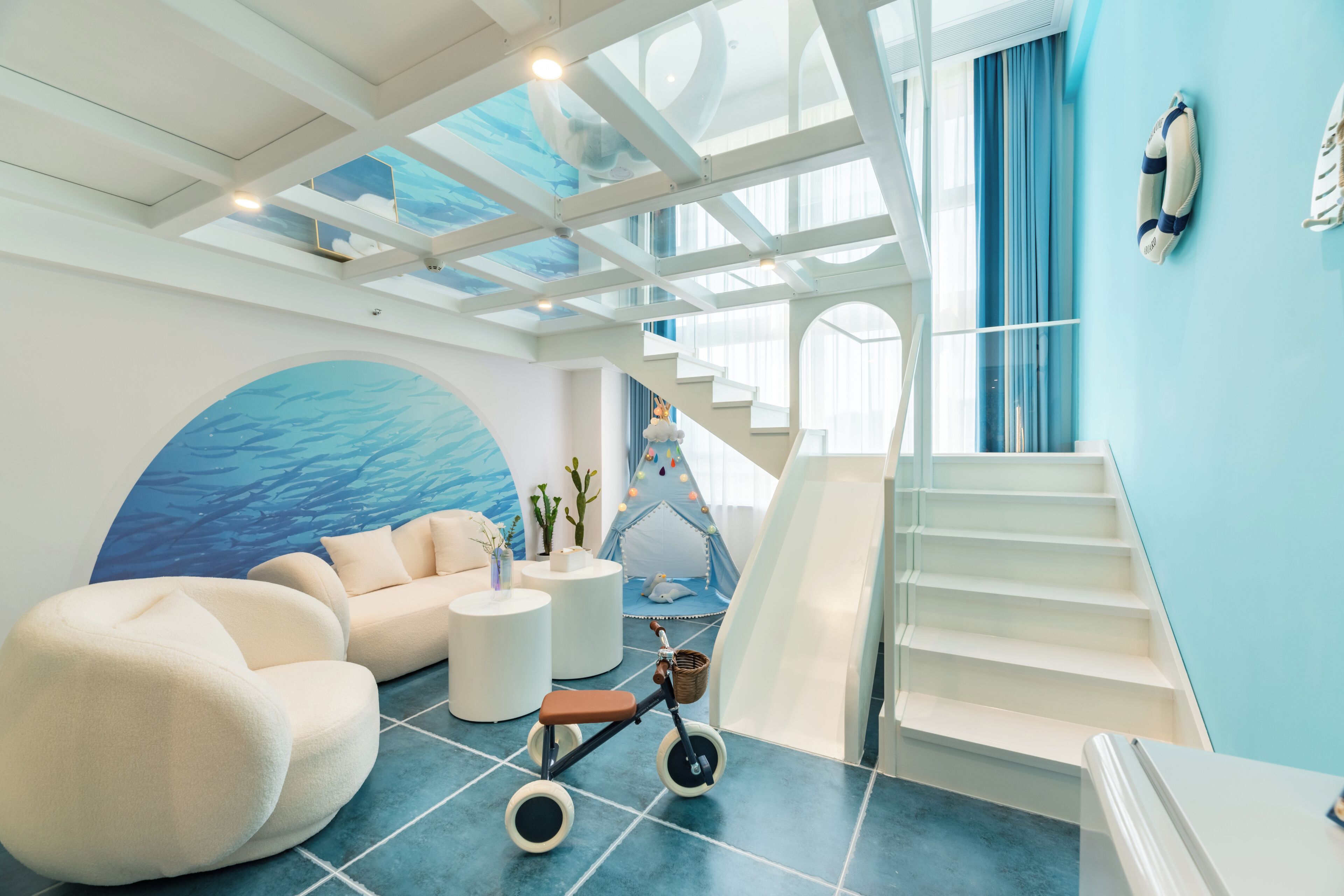 Un interior moderno con una escalera, una zona de juegos y un gran mural.