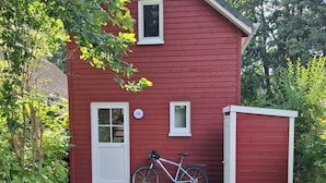 A red house with a white door, a bicycle parked in front, and a number 15 sign on the wall. - Holiday Home 'Am Wasser, Bootshaus' with Private Terrace (Güstrow)
