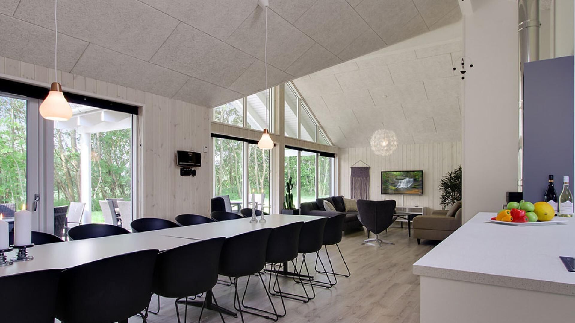 Une salle de conférence moderne, dotée d’une longue table, de chaises noires et de grandes fenêtres donnant sur l’extérieur.