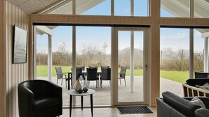 Amplia habitación con un amplio ventanal corredero que da a un patio exterior con sillas y una mesa.