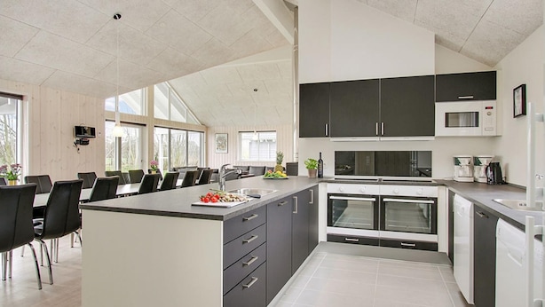 A modern kitchen with a central island, dark cabinets, and a microwave. - VillaVilla 712 - Olpenitz, Deutschland (Kappeln)