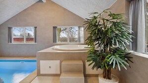 Ein modernes Badezimmer mit Badewanne, einem Fenster und einer Topfpflanze.